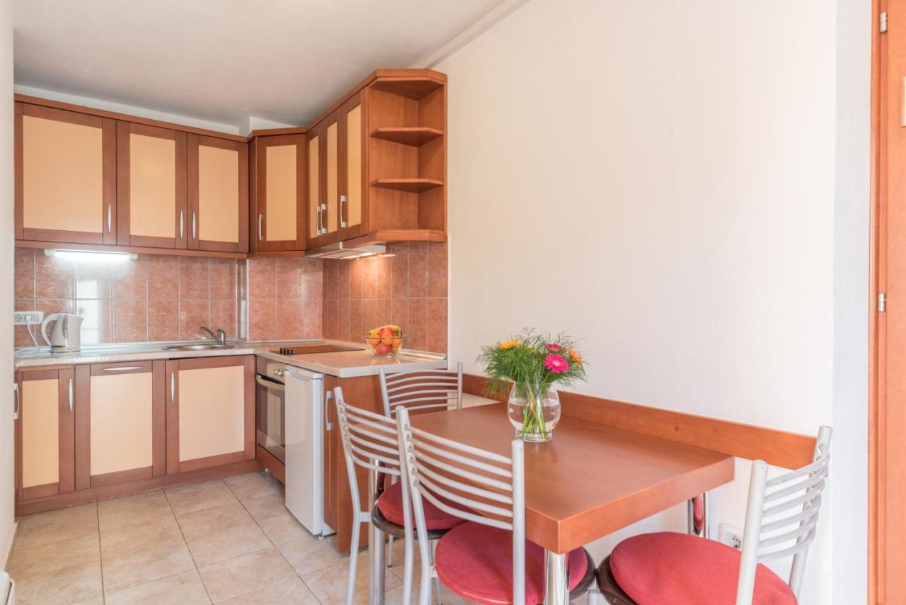 Compact kitchen with wooden table and chairs at R Club Apartments